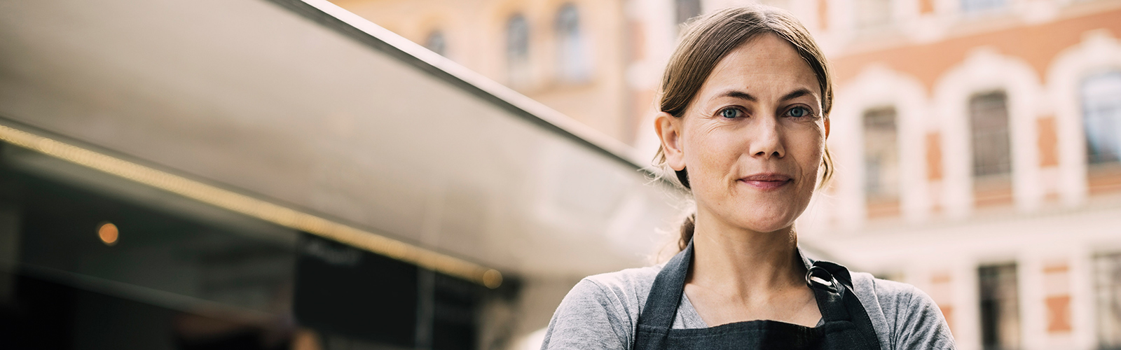 Vista frontale di una chef sicura di sé in piedi davanti a un chiosco ambulante in città Vista frontale di una chef sicura di sé in piedi davanti a un chiosco ambulante in città